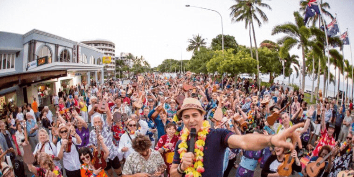 Large crowd of people playing ukuleles outdoors during a festive gathering in a city