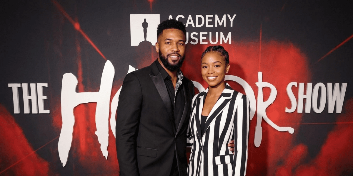 A man and woman pose together on a red carpet at an event.