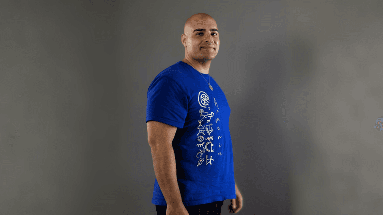 Arthur Palyan in a blue "Armenia" shirt, embodying transformation and self-empowerment for his mastermind event.