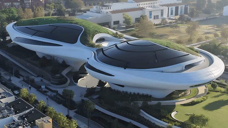 Futuristic building with green roofs and curved white structures surrounded by landscaped grounds