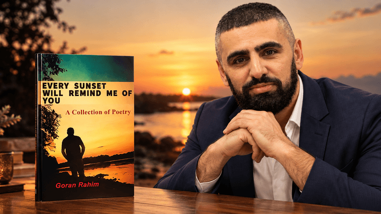 A man poses with his poetry collection against a sunset backdrop by the sea