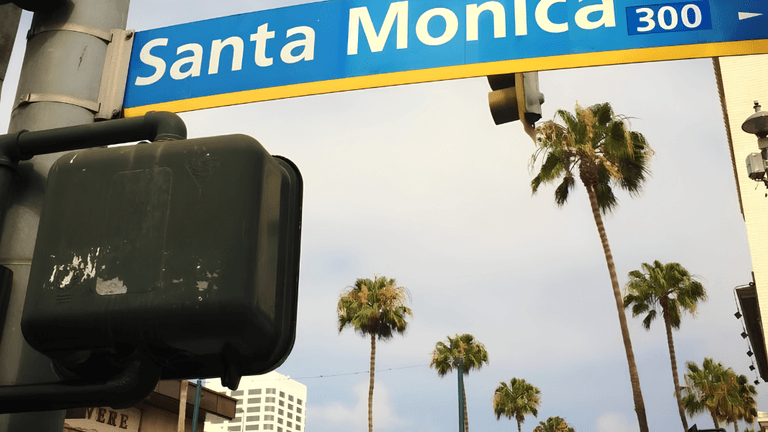 Santa Monica street sign with palm trees and a cloudy sky in the background