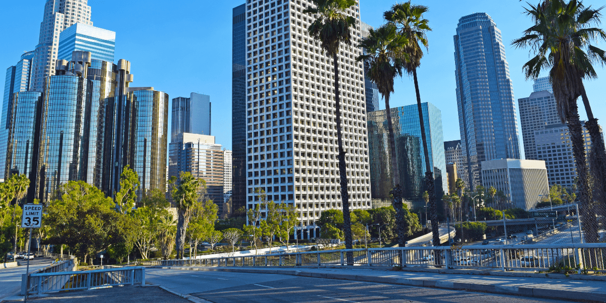 Skyline of downtown Los Angeles with palm trees and modern skyscrapers under blue sky
