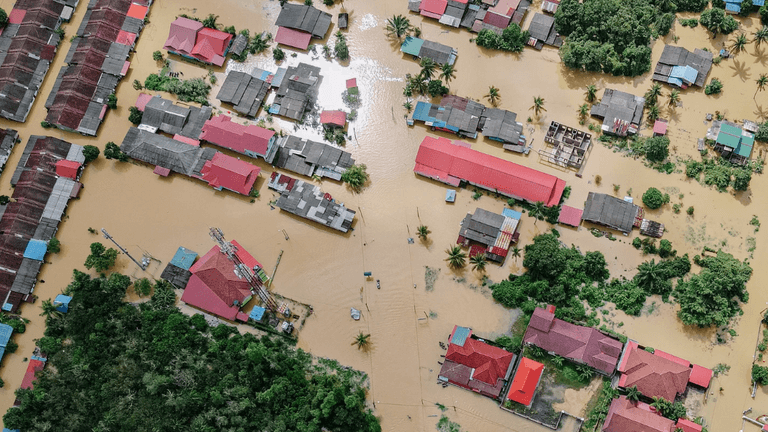 Aerial view of flooded residential area with submerged houses and trees visible