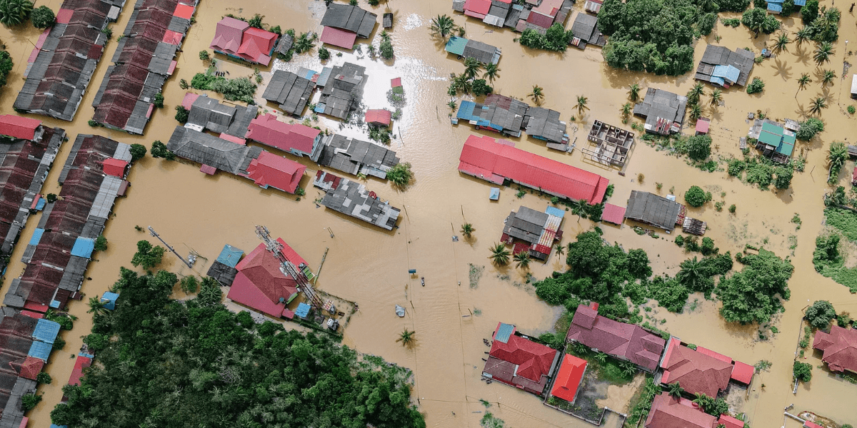 Aerial view of flooded residential area with submerged houses and trees visible