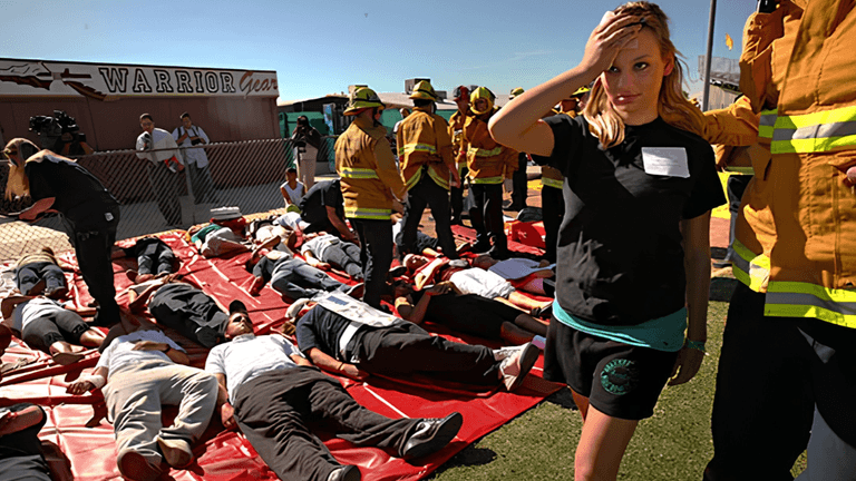 Emergency responders assist individuals lying on red mats during a disaster simulation exercise