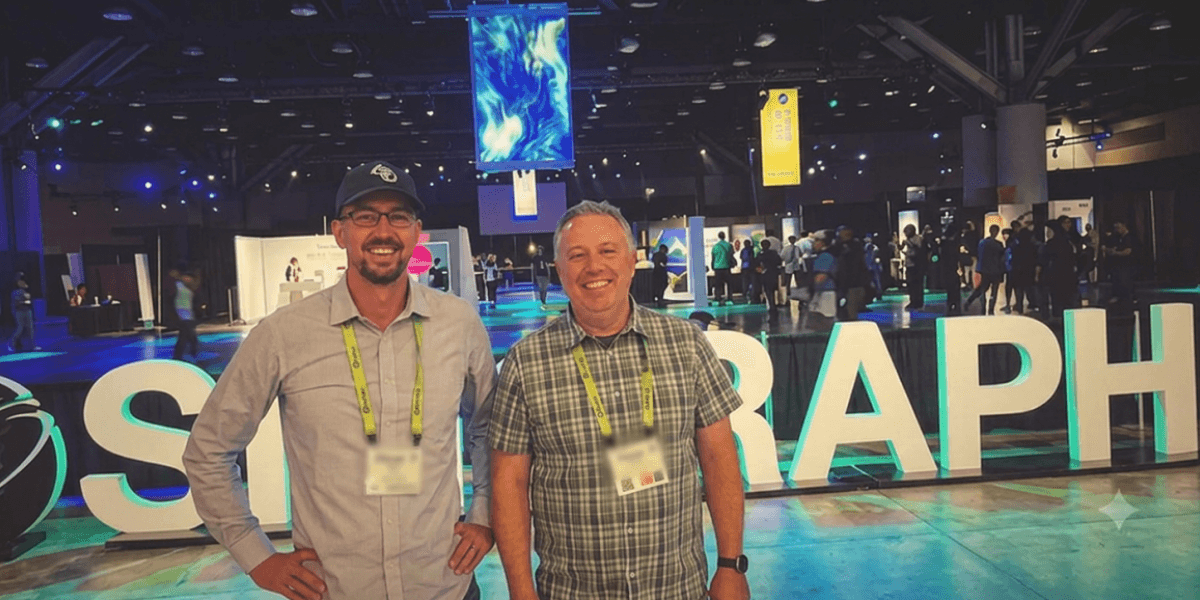 Two attendees standing in front of the illuminated SIGGRAPH sign at the SIGGRAPH 2026 conference in Los Angeles.