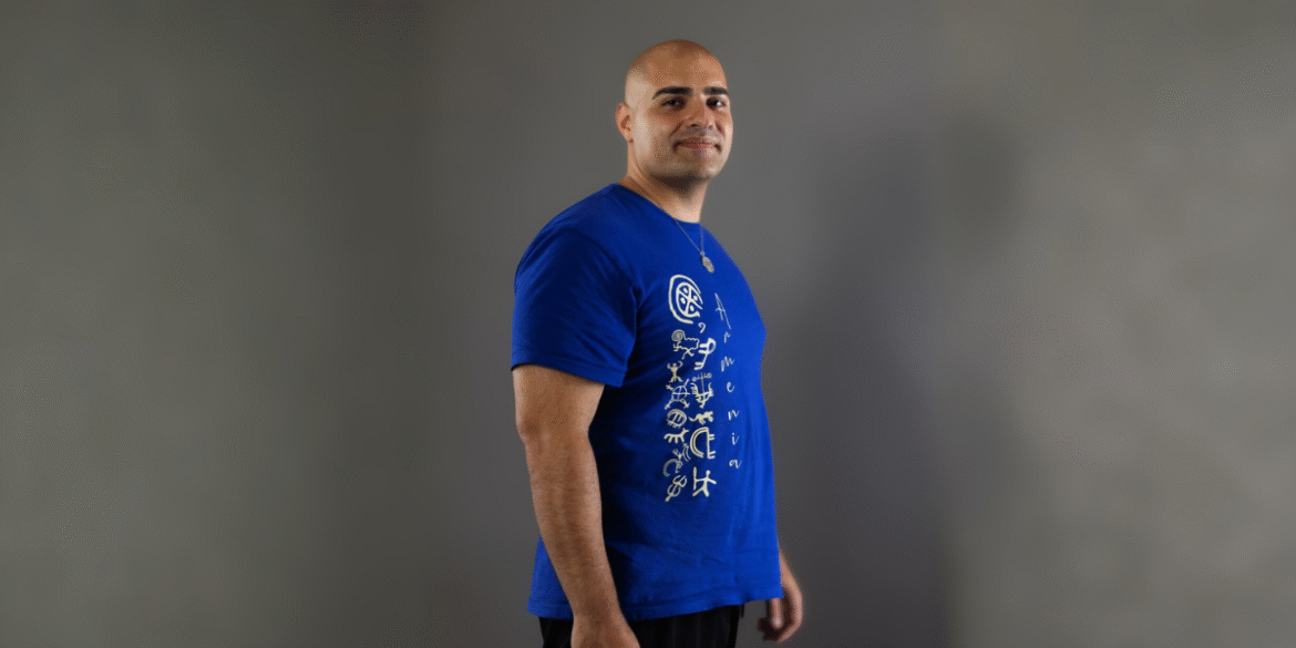Arthur Palyan in a blue "Armenia" shirt, embodying transformation and self-empowerment for his mastermind event.
